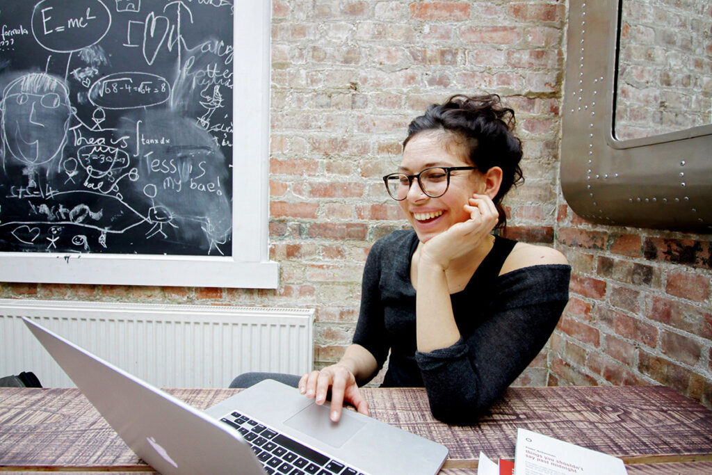 Mulher de frente para o computador sorrindo