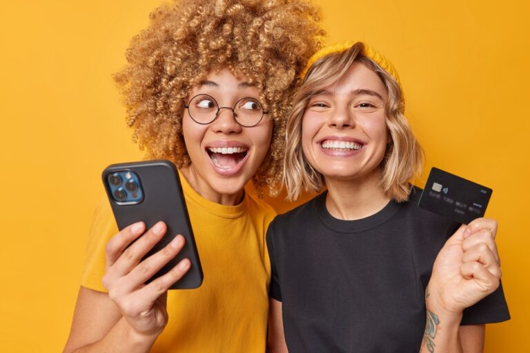 Duas mulheres sorrindo e uma segurando o celular