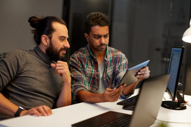 Dois homens sentados, olhando para computador