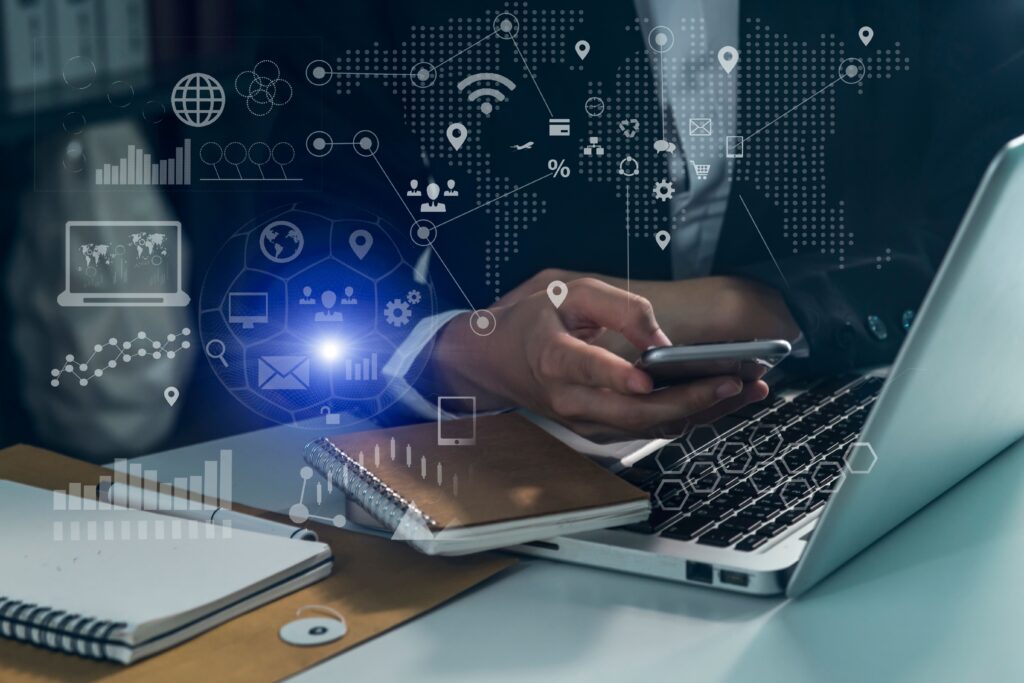 Businessman using a smartphone with computer keyboard at office on digital interface.